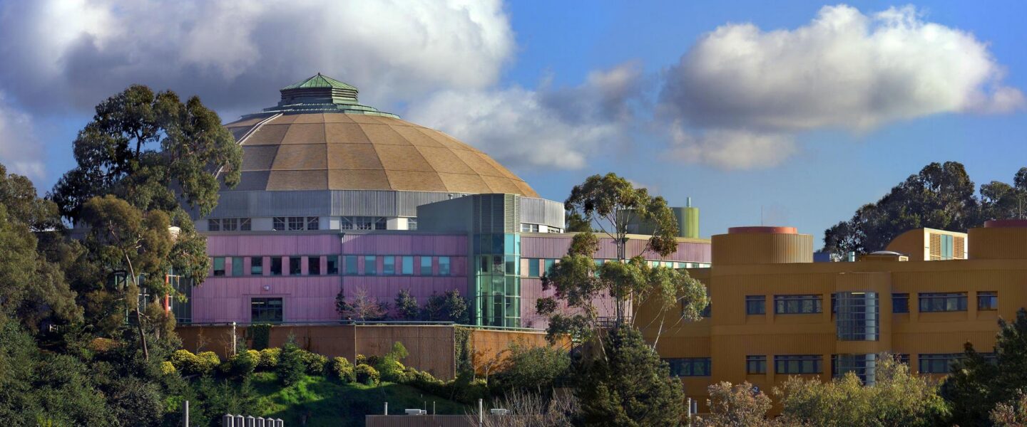 The Advanced Light Source in front of a blue, cloud-filled sky.