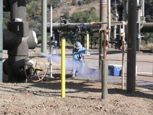 A technician from the Geysers Power Company samples steam condensate and gas from The Geysers geothermal field, providing baseline geochemical data for the DOE-funded Demonstration of a Deep Enhanced Geothermal System at the Northwest Geysers Geothermal Field, California.