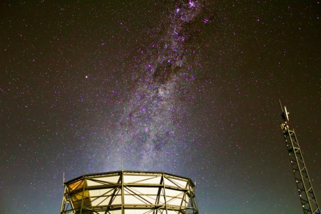 Photo - The Milky Way's galactic plane rises above the Atacama Cosmology Telescope. The Simons Observatory is planned at the same site and will merge existing experiments and add new telescopes and detectors. (Jon Ward/University of Pennsylvania)