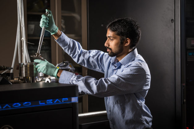 Image - Arun Devaraj, a staff scientist at PNNL, loads a sample into a chamber in preparation for an atom probe tomography experiment. This method, which can provide a nanoscale 3-D map of a chemical element’s distribution in a material, was used in combination with other techniques, including X-ray experiments at Berkeley Lab, to study a type of catalyst known as a zeolite. (Credit: PNNL)