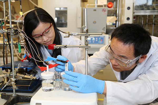 Photo - University of Toronto researchers Xueli Zheng, left, and Bo Zhang test a previous catalyst for the artificial photosynthesis system. The new catalyst works at lower pH, leading to an improvement in the overall efficiency of the system. (Credit: Marit Mitchell/University of Toronto)