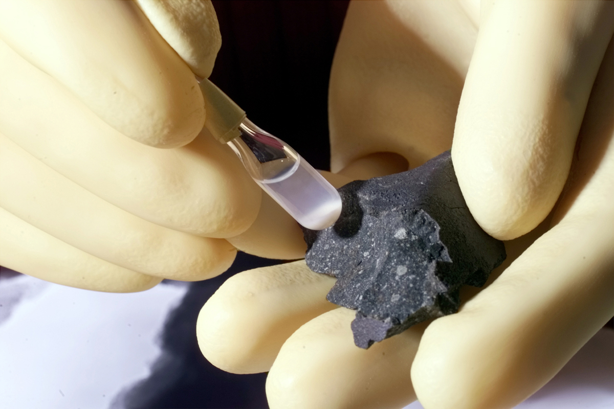 Photo - A researcher handles a fragment of the Murchison meteorite, which has been shown to contain a a variety of hydrocarbons and amino acids, and test tube samples from the meteorite, in this photo from a previous, unrelated study. Experiments at Berkeley Lab are working to retrace the chemical steps by which complex hydrocarbons could form in the Murchison meteorite and other meteorites rich in organic material. (Credit: Argonne National Laboratory) 