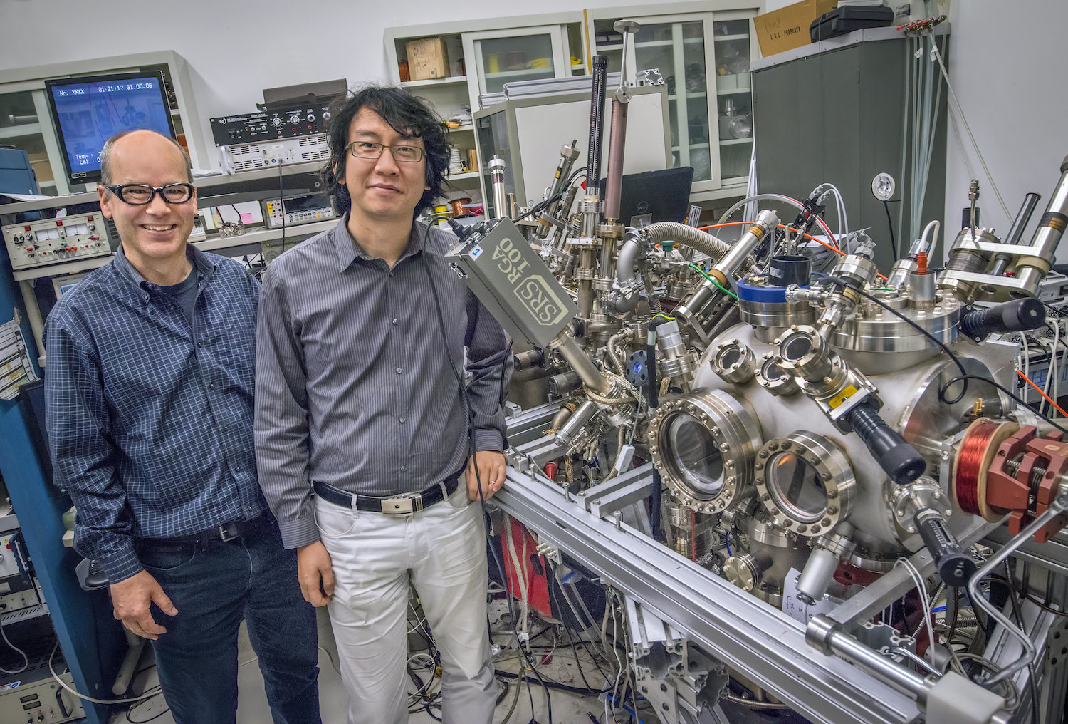 Photo - Andreas Schmid, left, and Gong Chen are pictured here with the spin-polarized low-energy electron microscopy (SPLEEM) instrument at Berkeley Lab that was integral to magnetic measurements of ultrathin samples that included graphene and magnetic materials. (Credit: Roy Kaltschmidt/Berkeley Lab)