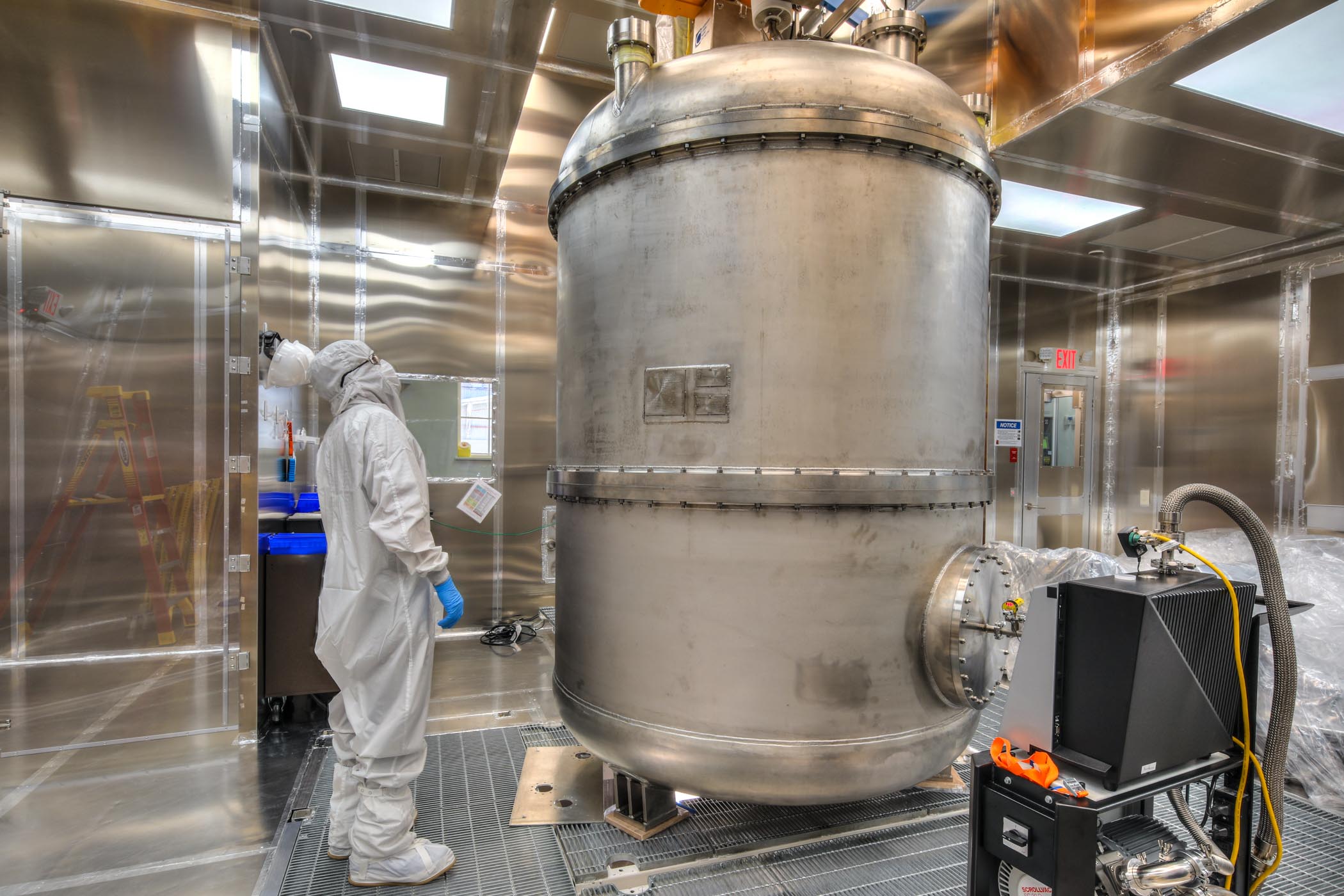 Photo - A worker inspects the titanium cryostat for the LUX-ZEPLIN experiment in a clean room. (Credit: STFC)