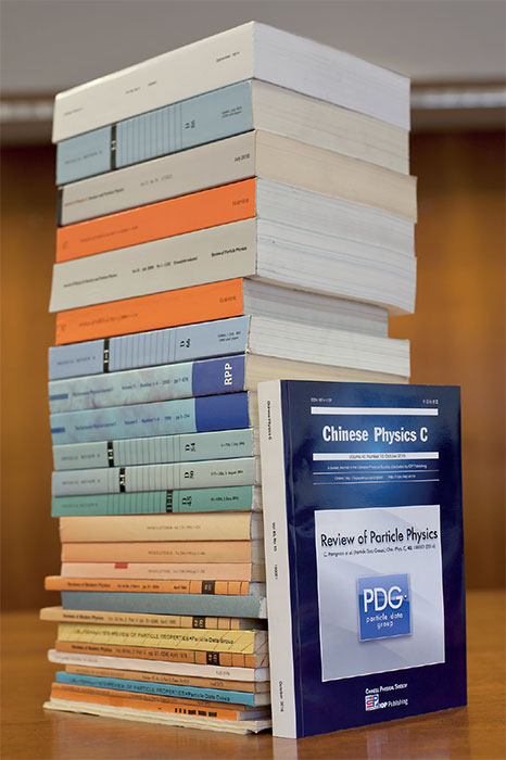 Photo - Today marks the release of the 2018 print edition of the Review of Particle Physics. In this photo, a copy of the printed 2016 edition leans against a stack of previous editions in this photo, with the oldest issues at the bottom. (Credit: Lawrence Berkeley National Laboratory.)