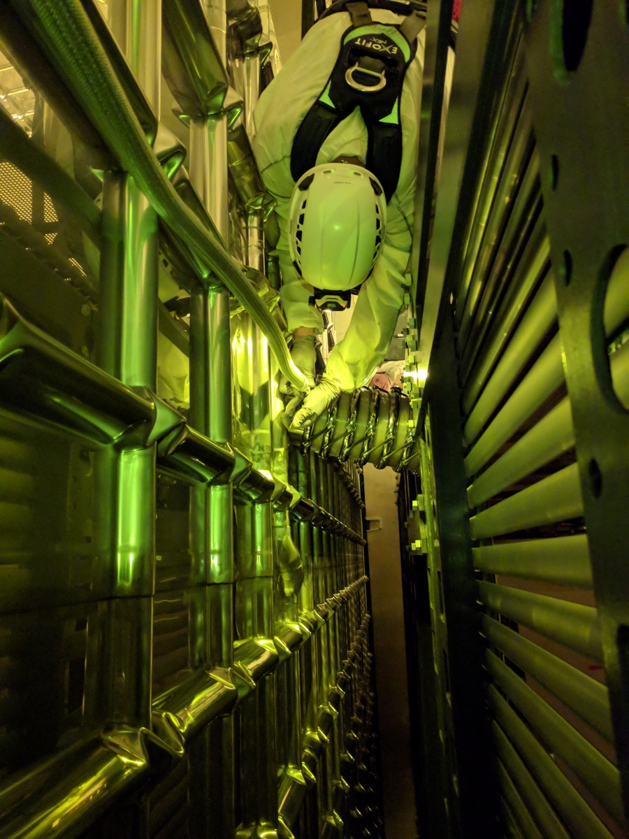 Photo - A team from Berkeley Lab worked on installation of the beam window – the cylindrical, ringed object in the middle of the photo – for ProtoDUNE. A particle beam at CERN enters the cryostat wall from the left of the photo, through the middle of the beam window, and then gets injected into the detector volume shown at the right of the photo. The region shown in the photo has since been filled with liquid argon chilled to minus 301 degrees Fahrenheit. (Credit: CERN)