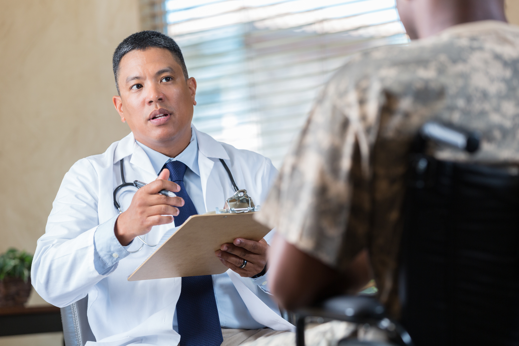 A photo of a male doctor speaking with a veteran in a wheelchair.