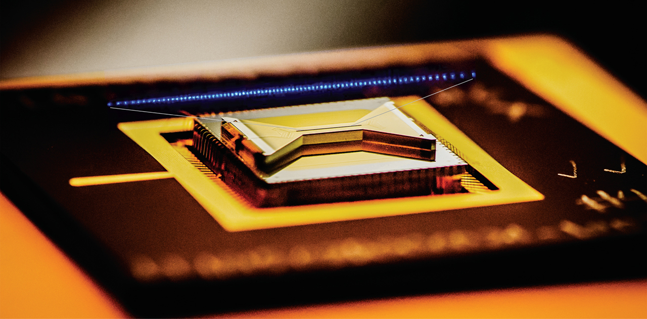 A semiconductor chip ion trap, fabricated by Sandia National Laboratories and used in research at the University of Maryland, composed of gold-plated electrodes that suspend individual atomic ion qubits above the surface of the bow-tie shaped chip.