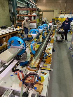 Photo - Berkeley Lab technicians Ahmet Pekedis, left, and Joshua Herrera assemble the third pre-production magnet for the HL-LHC AUP project. The magnet is expected to ship to Brookhaven National Laboratory for testing in September. (Credit: Dan Cheng/Berkeley Lab)