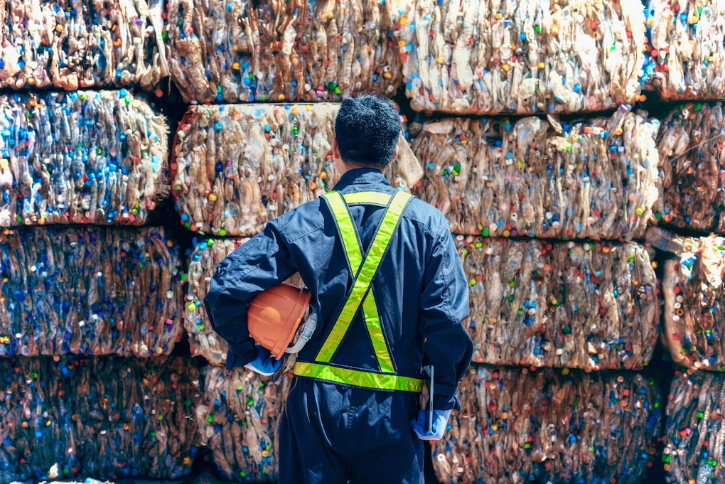Person standing in front of plastic compressed recycling blocks