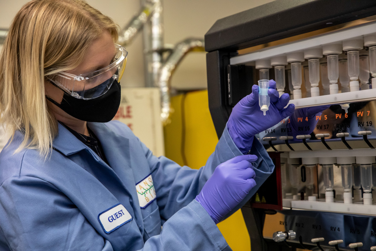 A blonde researcher wearing a blue lab coat holds a antiviral sample at the Molecular Foundry.