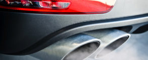 Silver car with smoking exhaust pipes.