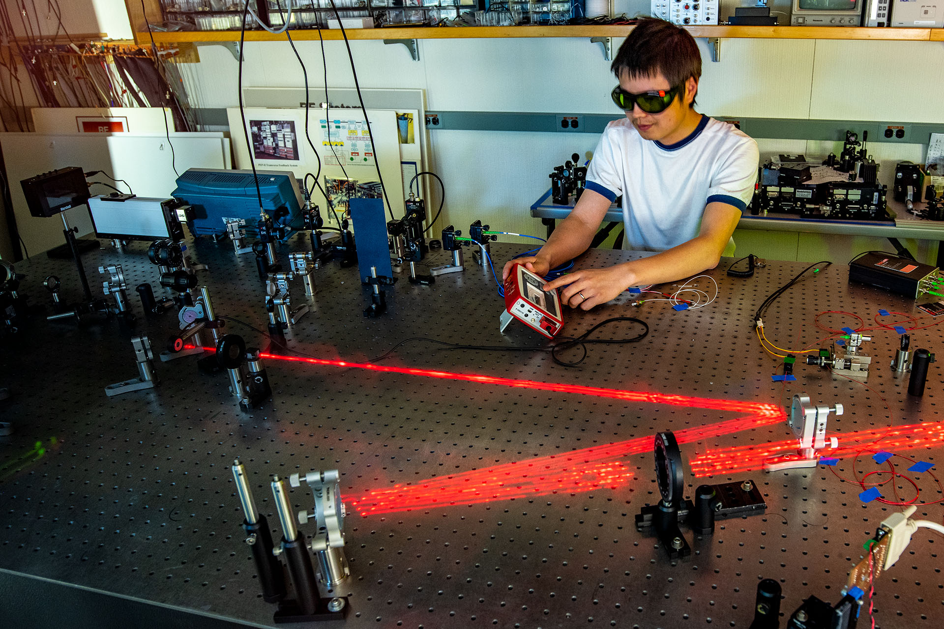 Photo of Berkeley Lab scientist Tong Zhou working on lasers at a lab table.