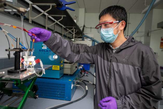 Guiji Liu, a Liquid Sunlight Alliance project scientist in Berkeley Lab’s Chemical Sciences Division, adjusts a photoelectrochemical cell. (Credit: Thor Swift/Berkeley Lab)