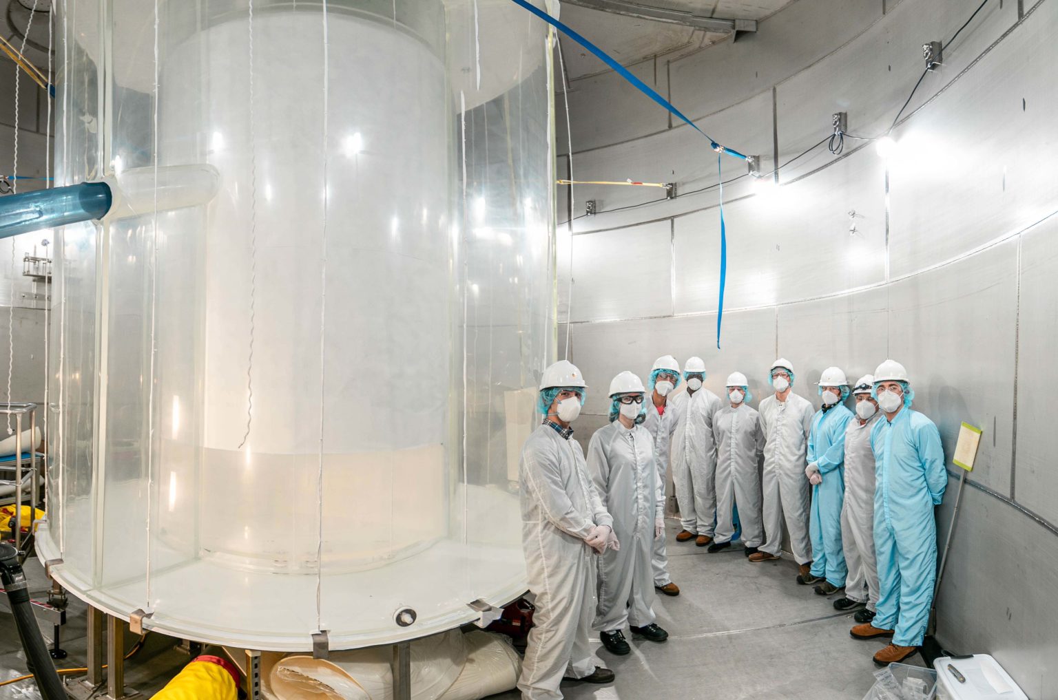 Members of science team lined-up in a water tank after the outer detector installation.