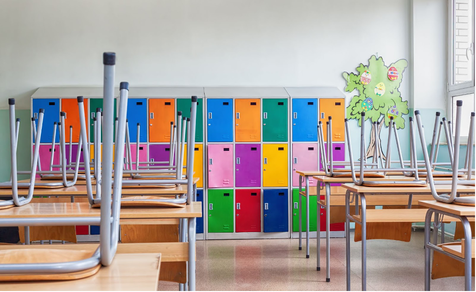 Chairs stacked on top of desks in a school classroom.