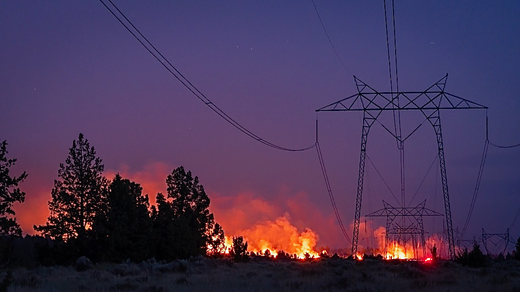 A wildfire blazes under power lines.