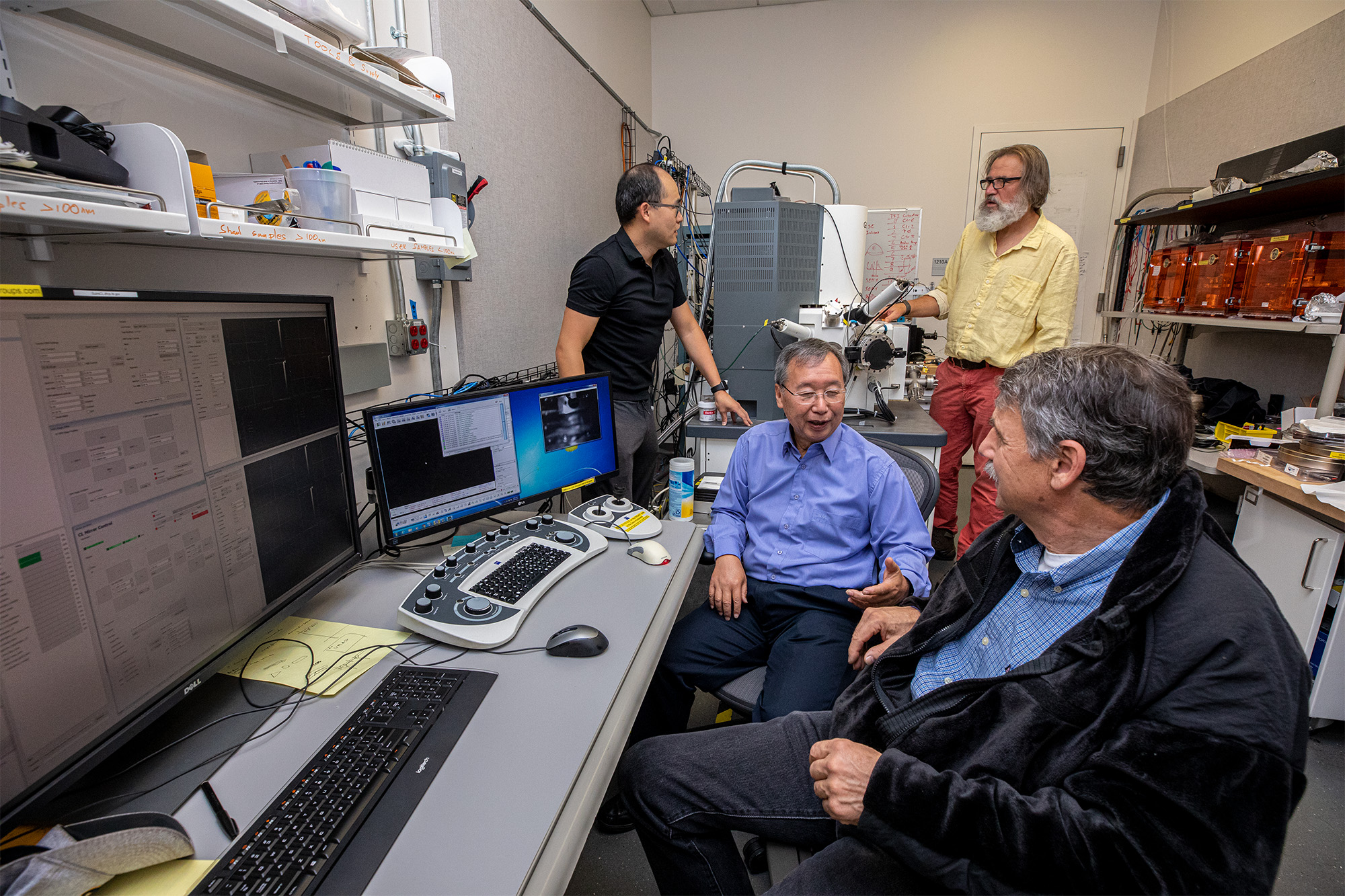 Four scientists converse with each other in a lab.