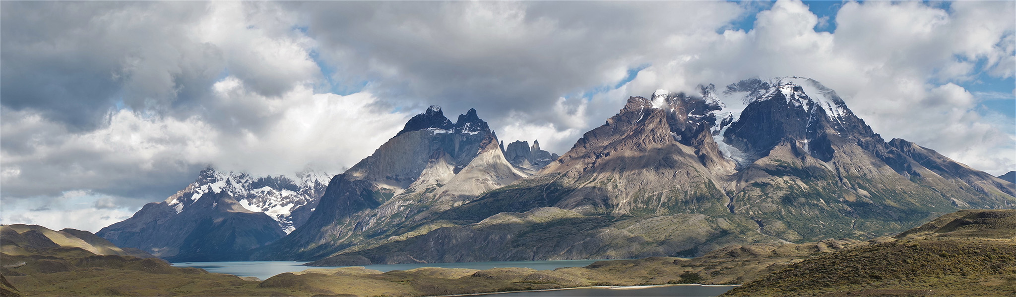 View of the snow-capped Chilean Andes (Torres del Paine National Park) with clouds overhead.