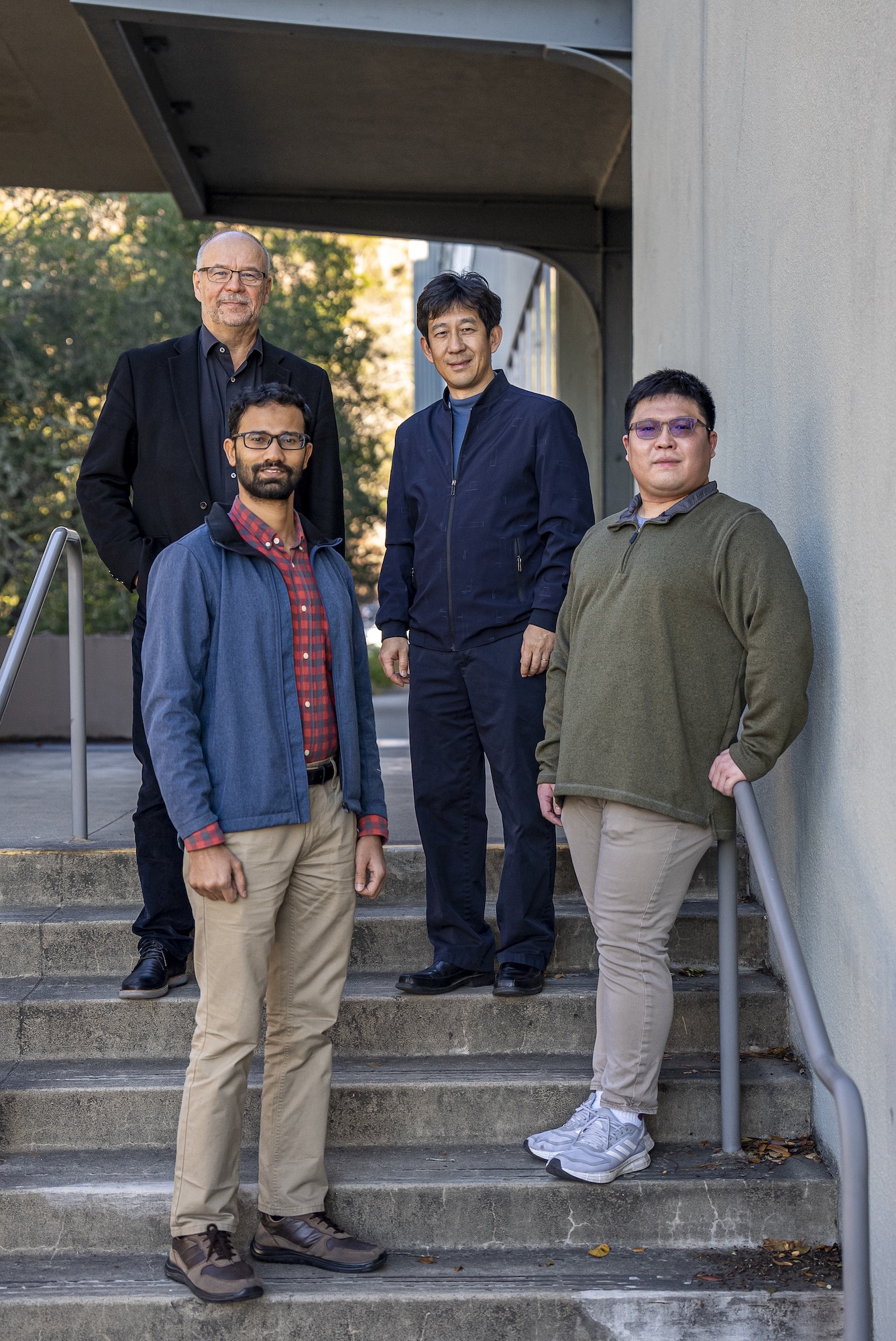 Four scientists standing on a stair case outside