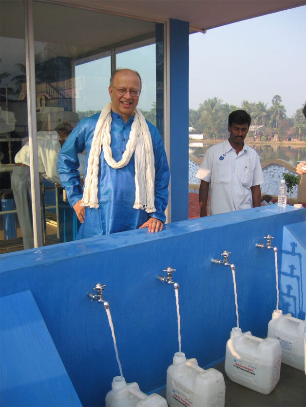Ashok Gadgil stands in front of a safe drinking water station in Mudinepalli, India.