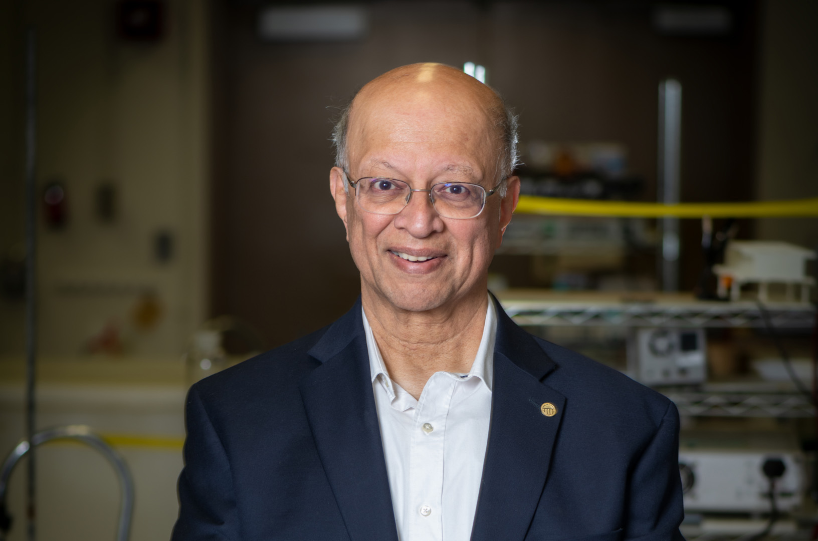 Ashok Gadgil wearing a black suit jacket and white collared shirt, photographed in his lab.