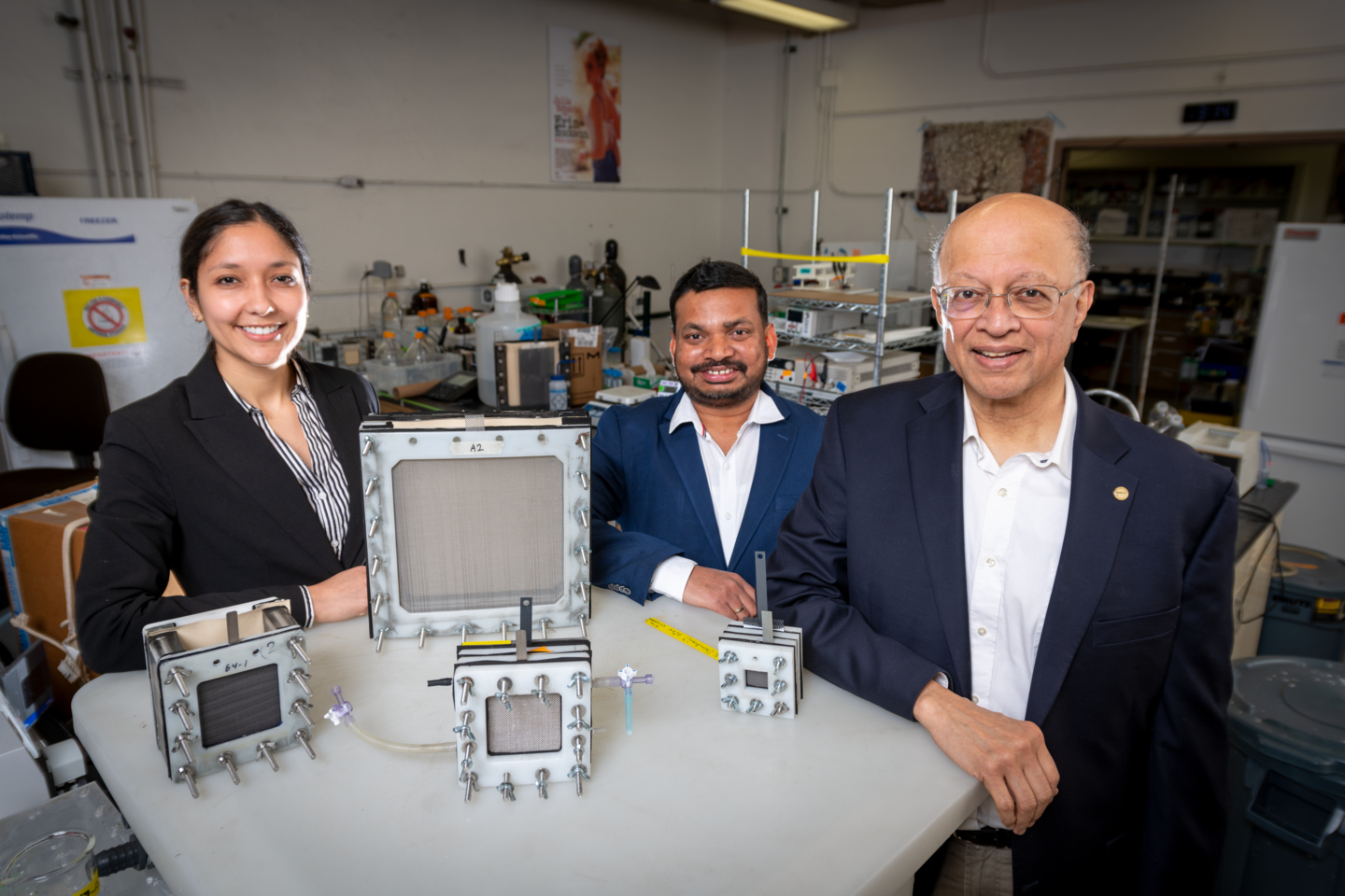 From left: Dana Hernandez, Siva Bandaru, and Ashok Gadgil sitting at a table with the arsenic filters they developed.