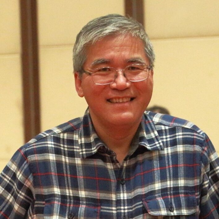 Smiling person in glasses and blue checkered flannel shirt.
