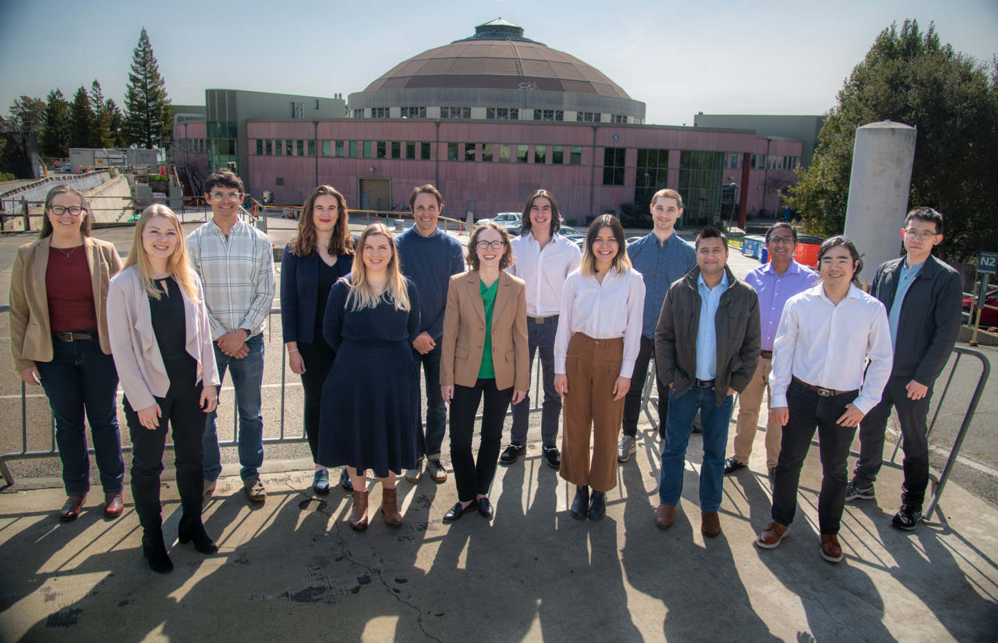 Berkeley Lab’s Technoeconomic Analysis Team, a group of 14 people stand outside for a photo, with the Advanced Light Source visible in the background.
