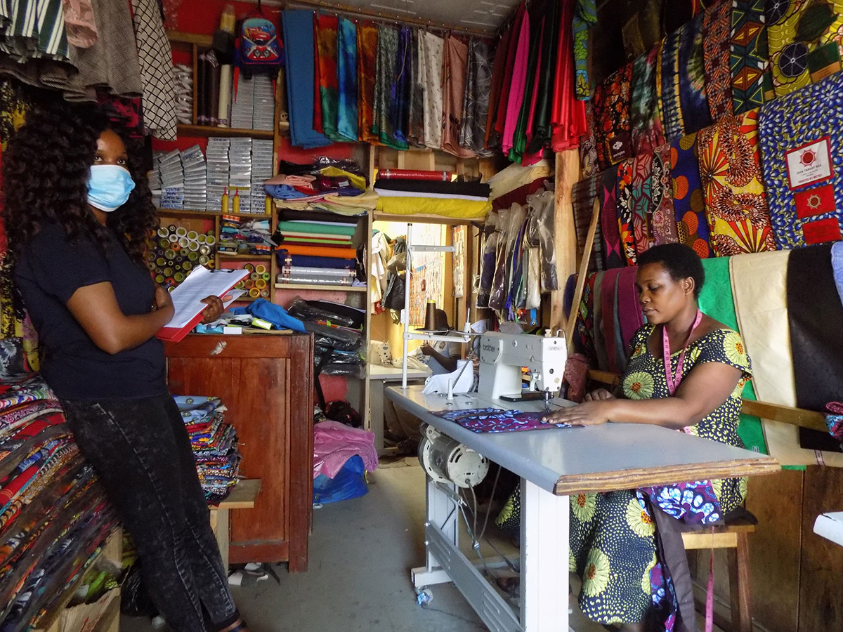Two women standing at opposite sides of a colorful sewing room.