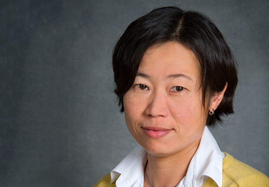 Junko Yano, a person with short dark hair wearing a yellow cardigan over a white collared shirt.