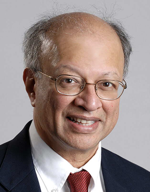 Ashok Gadgil, a person with short gray hair wearing glasses and a suit in front of a gray backdrop.
