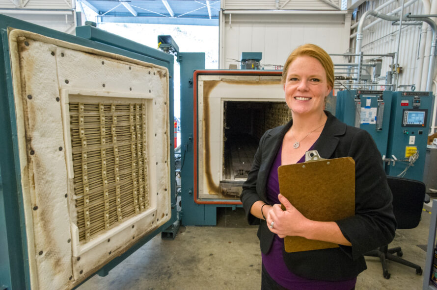 Dawn Munson, a person with hair tied back holding a clipboard at the Building 77 machine shop.