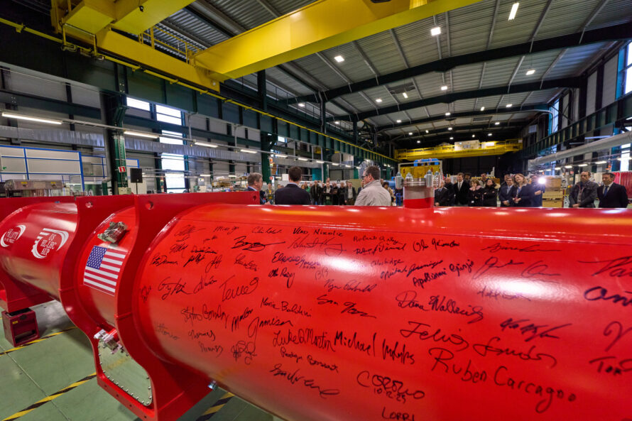Close-up of the U.S.-built HL-LHC magnet with signatures and a U.S. flag.