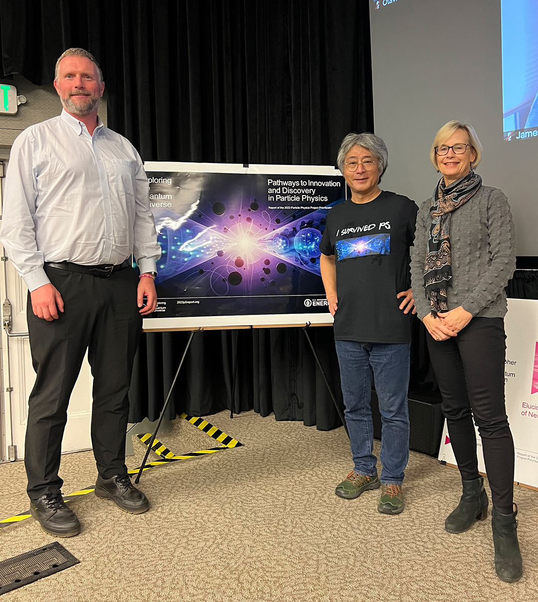 Three people (Cameron Geddes, Hitoshi Murayama, and Natalie Roe) standing in front of a poster in a conference hall.