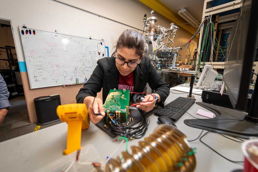 A person testing electronics that are part of the experimental setup used for making qubits in silicon in a lab.