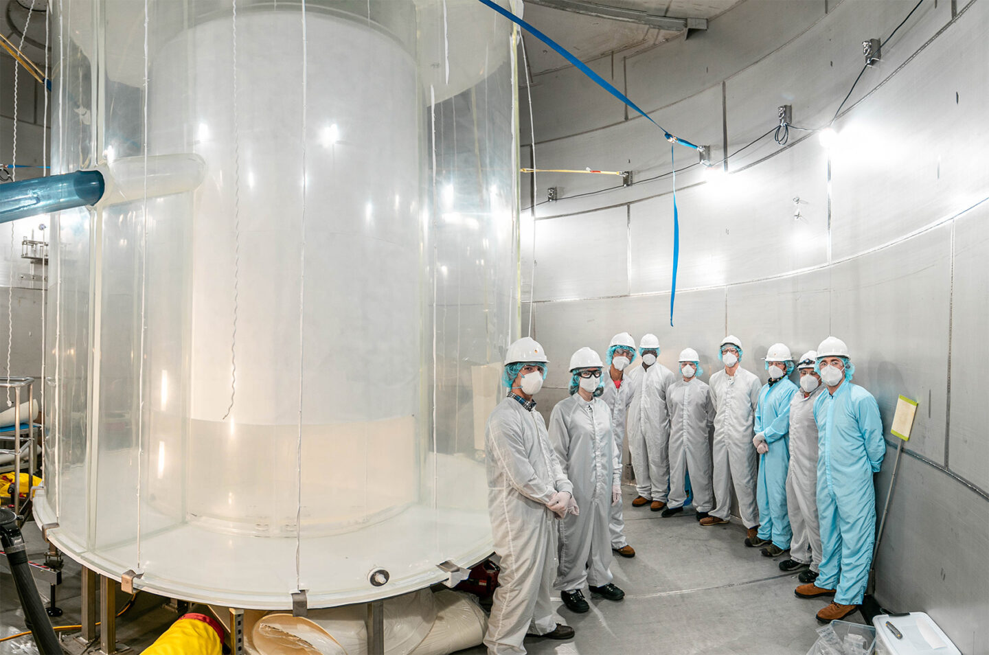 Members of the LZ team clad in protective gear in the LZ water tank after the outer detector installation.