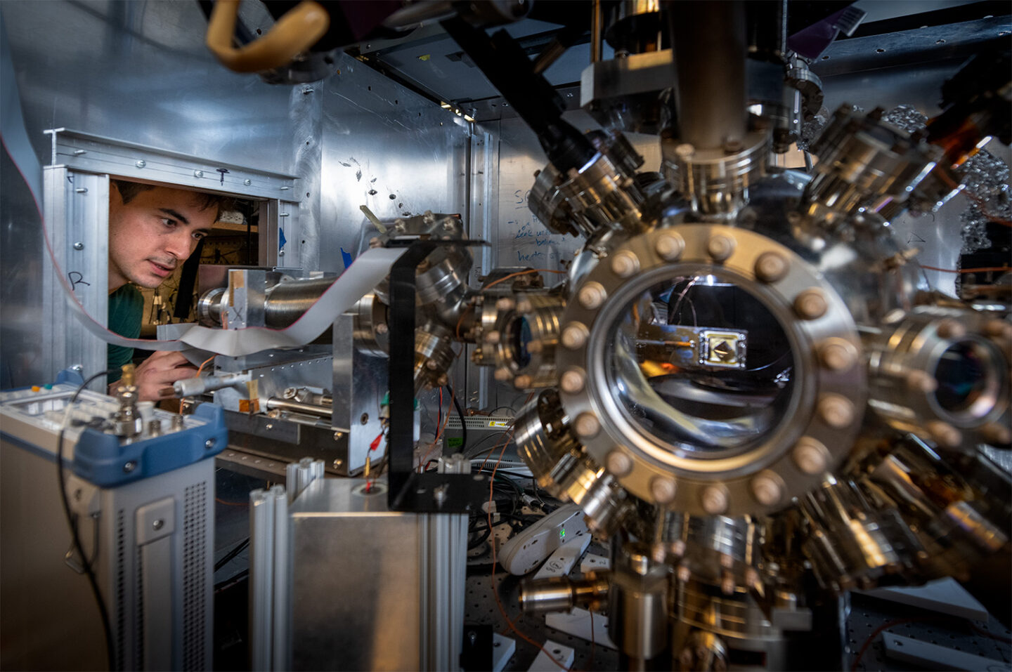 Graduate student Ben Saarel adjusts the settings on a vacuum apparatus used to make trapped ion qubits on the UC Berkeley campus.