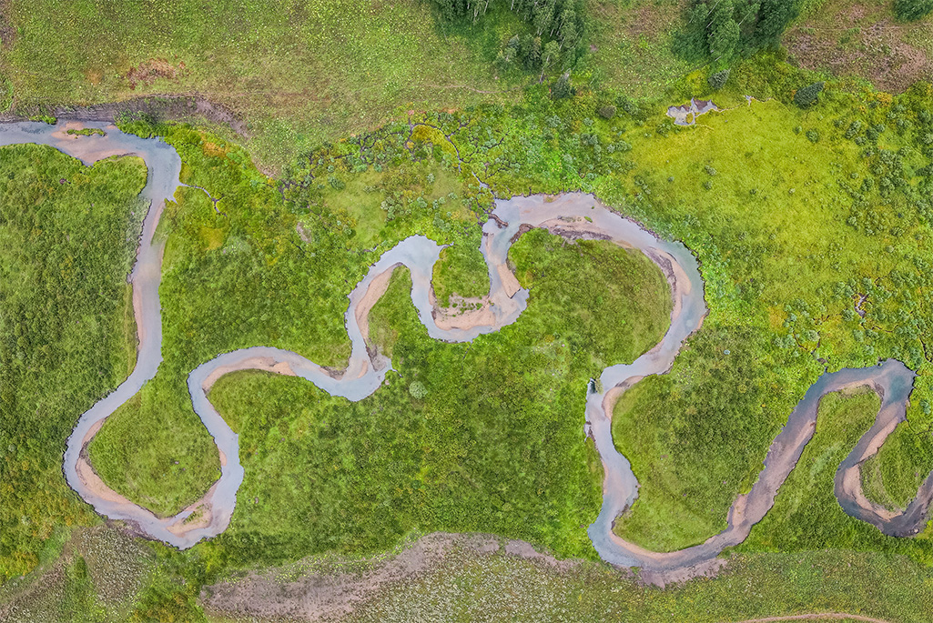 Aerial view of a winding river snaking through a green landscape.