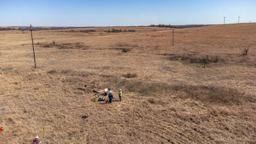 A team of people setting up sensors at a leaking well in the middle of a field.