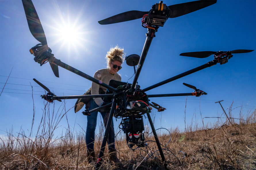 A person preparing a camera on a drone outdoors.