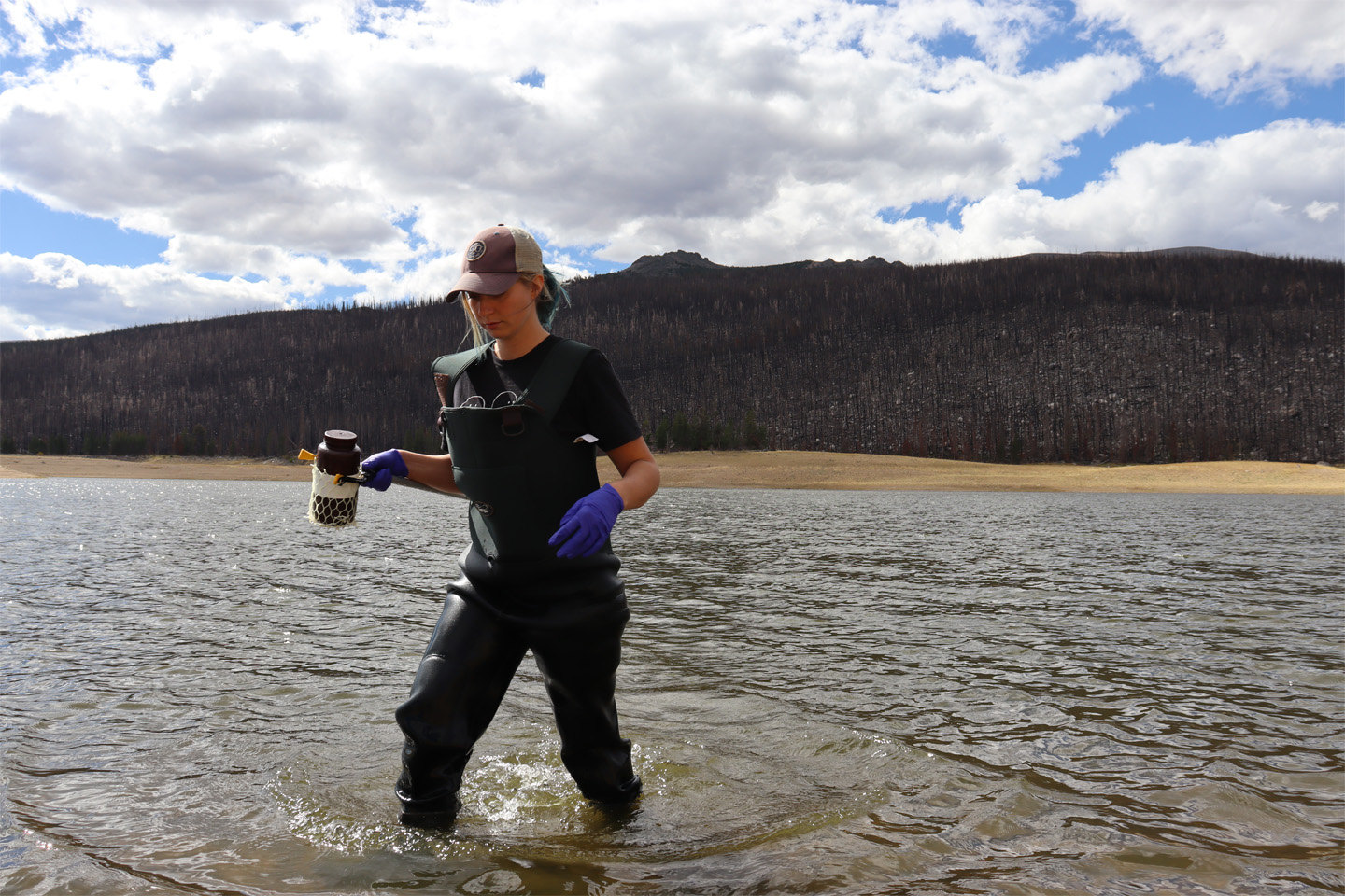 A pesron wading through a river with a bottle.