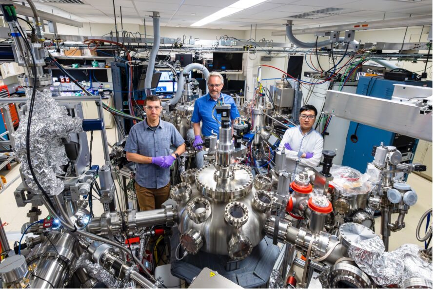 Three researchers wearing purple gloves, posing for the camera in their lab.