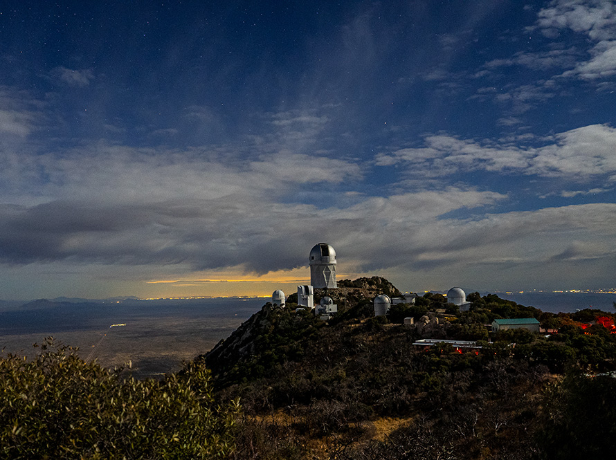 Multiple domed buildings on a mountainside. The sky is scattered with clouds.