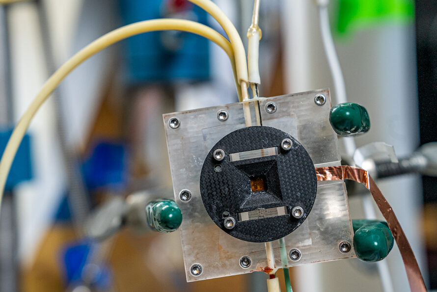 Close-up of a square metal and plastic lab component with tubes and copper wiring connected.