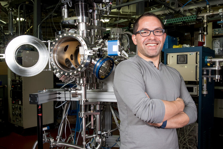 A researcher posed next to a scientific beamline.
