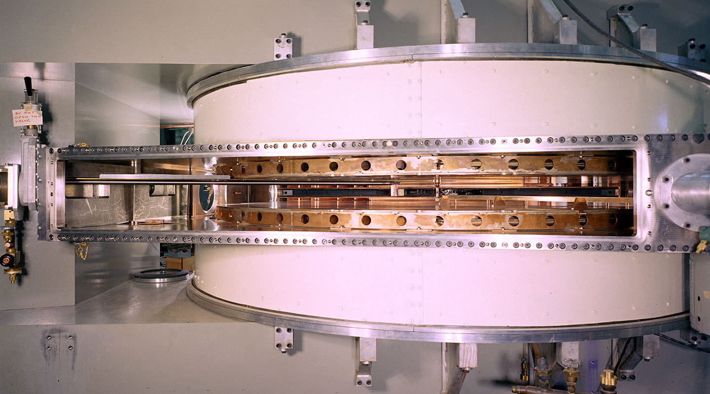 Close-up view of the white and copper circular center chamber of the 88-Inch Cyclotron, sandwiched between rectangular gray blocks.