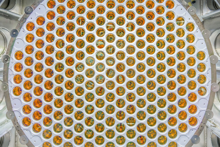 A circular array of amber, glossy photomultiplier tubes arranged in a grid pattern.