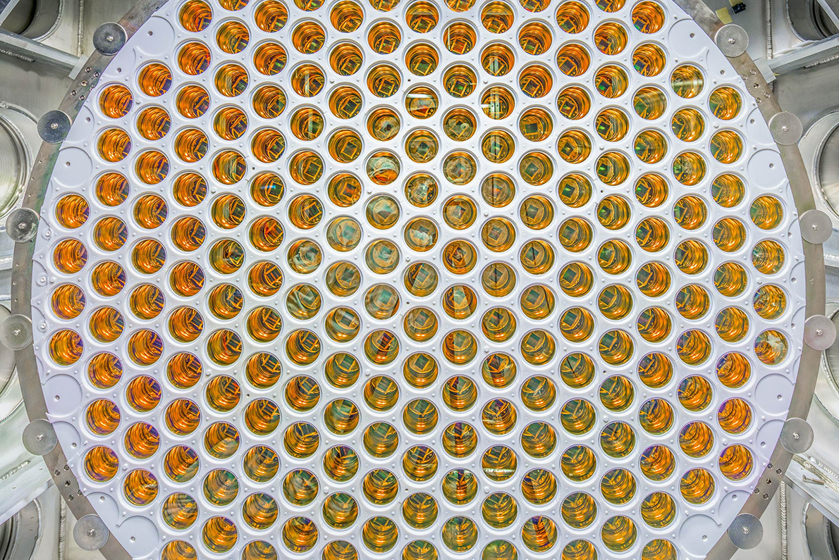 A circular array of amber, glossy photomultiplier tubes arranged in a grid pattern.