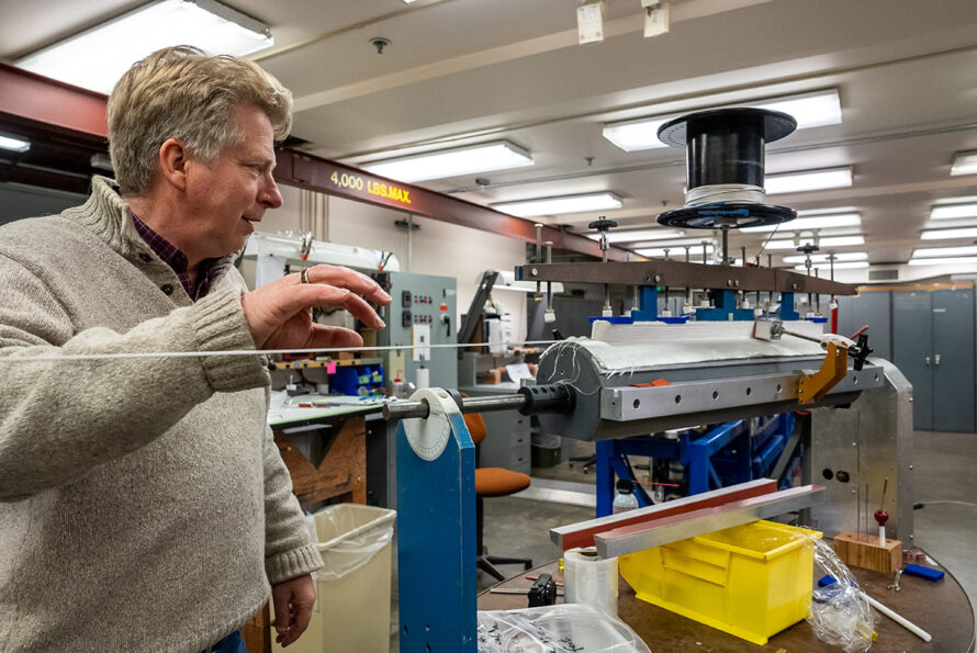 A scientist looks over a complex winding tool used to create magnets.